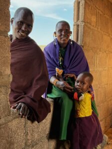A Maasai family in colorful traditional attire inside a rustic building in Kilimanjaro, Tanzania.
